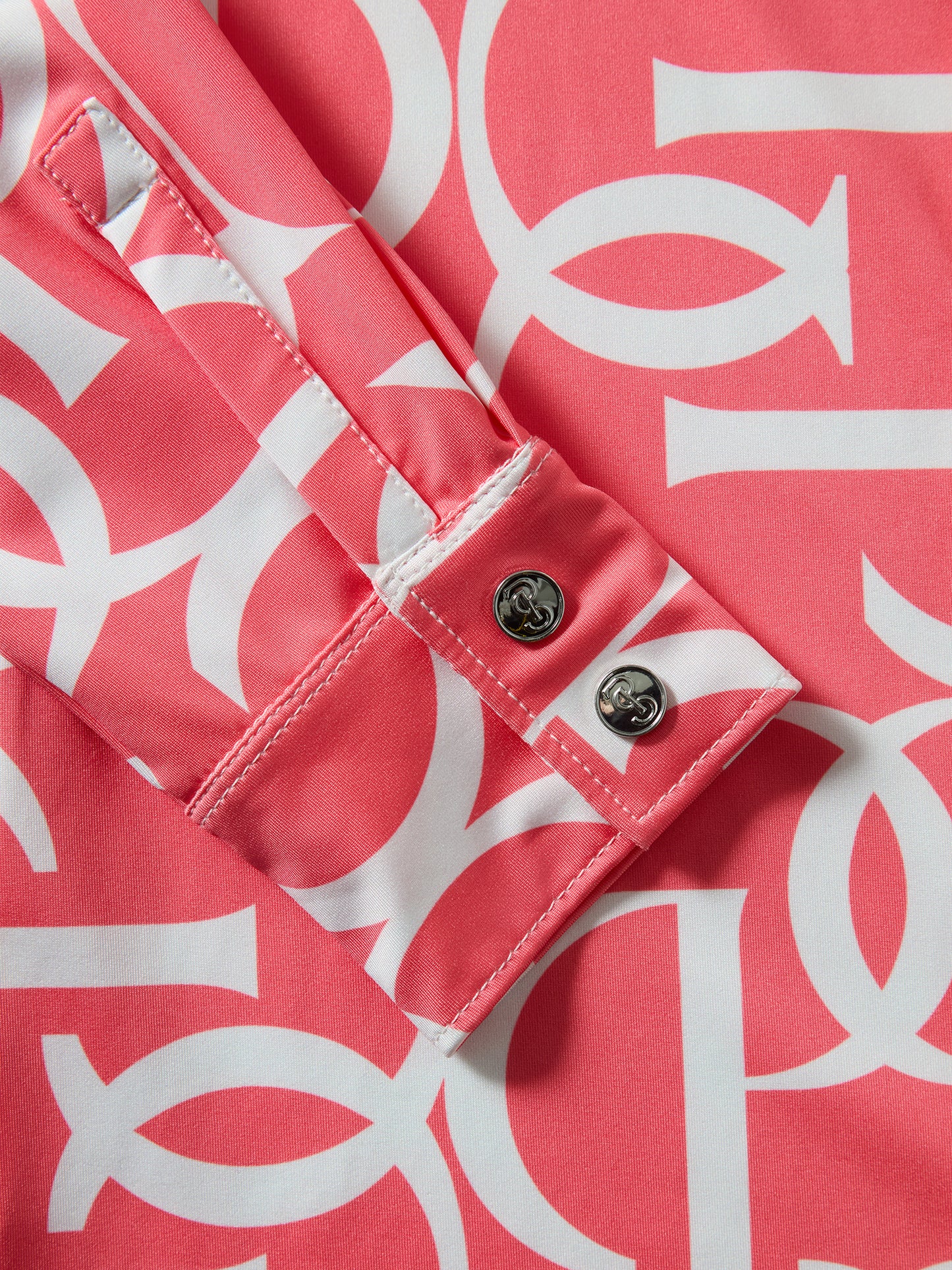 Close-up of a pink top with white geometric pattern and buttons.