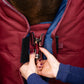 Person adjusting a horse's rug with a close-up of hands and front closure hardware.