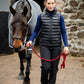 Woman walking a horse in grey leader equine wool horse rug in front of a stone wall.