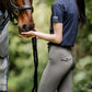 woman in equestrian breeches by leader equine and navy cotton t-shirt with horse in fly rug