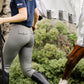 women in equestrian breeches in grey and navy cotton tshirt leading horse in fly rug by leader equine