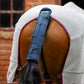 Close-up rear view of a horse wearing a grey cooler blanket with burgundy trim and a navy blue tail wrap, set against a brick stable background.
