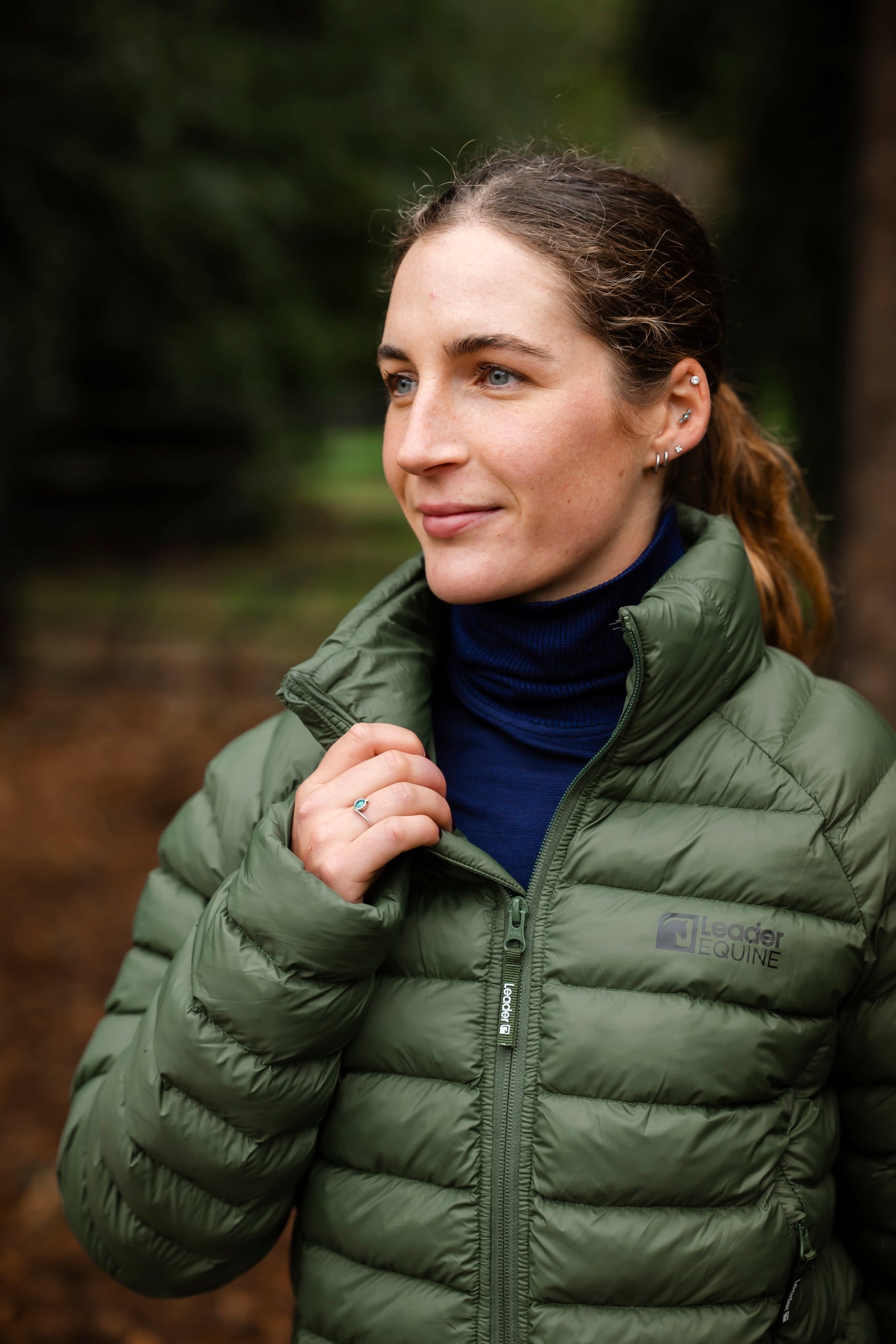 Woman wearing a green puffer jacket in a forest setting