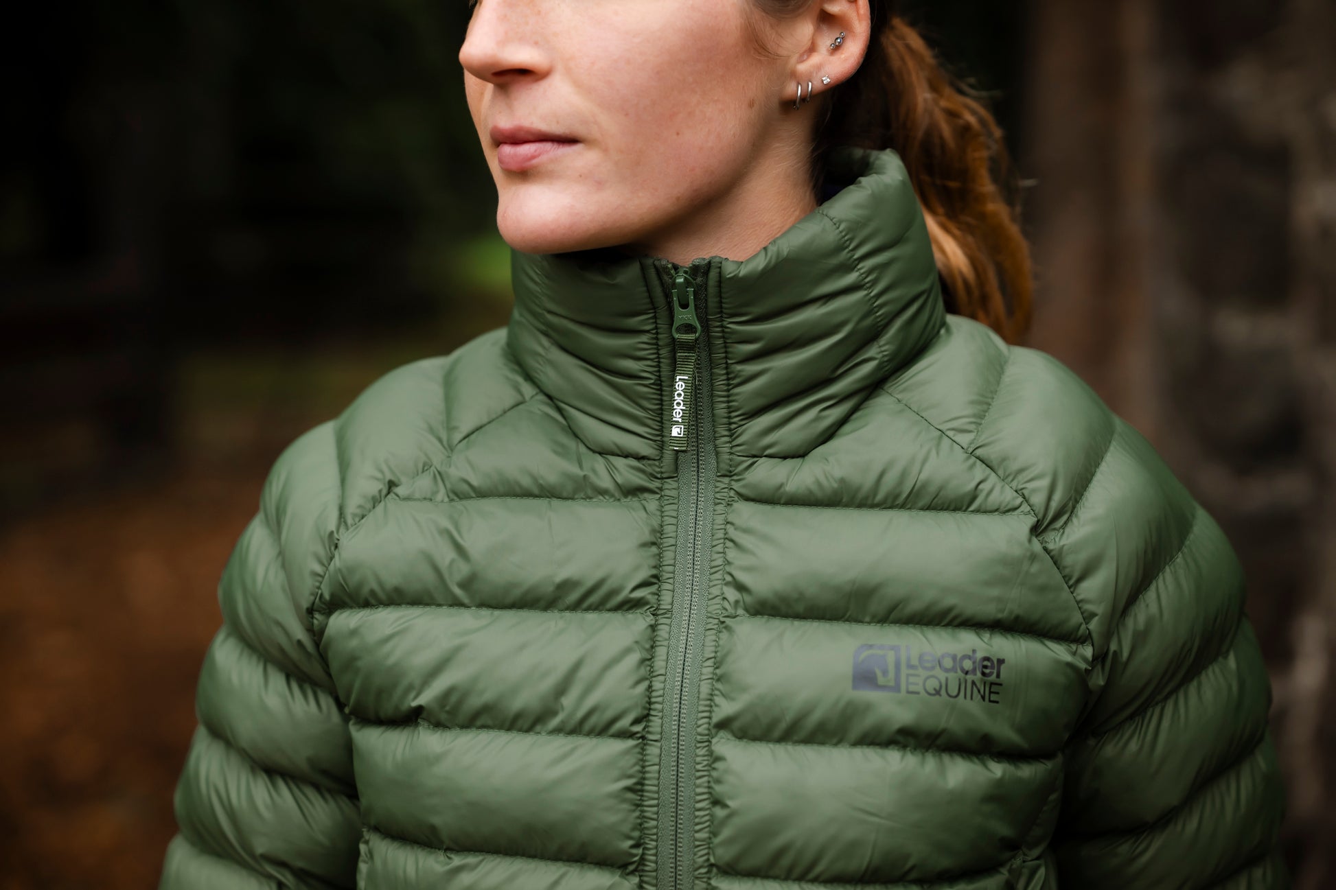Person wearing a green puffer jacket with a brand logo, standing outdoors.