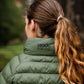 Person wearing a green puffer jacket with 'Leader Equine' branding, standing outdoors.