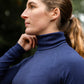 Woman wearing a blue leader equine sweater outdoors with blurred greenery in the background