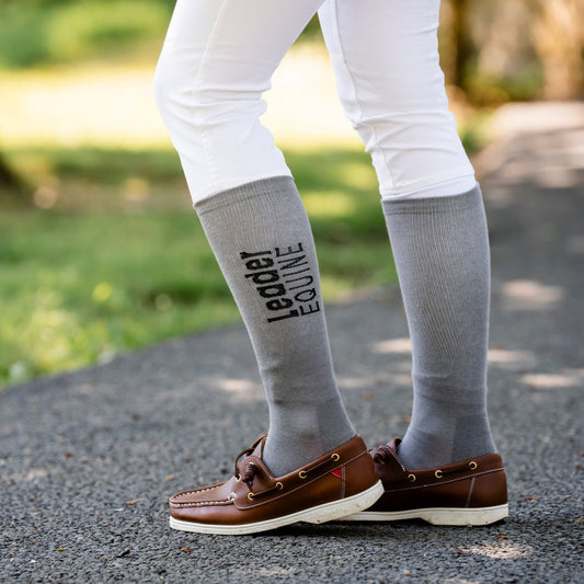 Person wearing Leader Equine Knee high socks in grey, over white breeches.