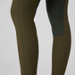 Close-up of a person's legs wearing ps of sweden leggings in olive green with suede knee patch, shown against a light gray studio background.