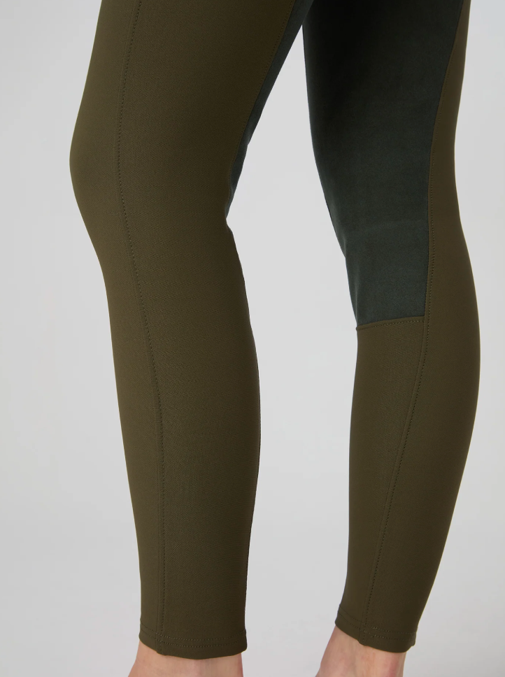 Close-up of a person's legs wearing ps of sweden leggings in olive green with suede knee patch, shown against a light gray studio background.