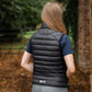 Person wearing a black puffer vest in a forest setting