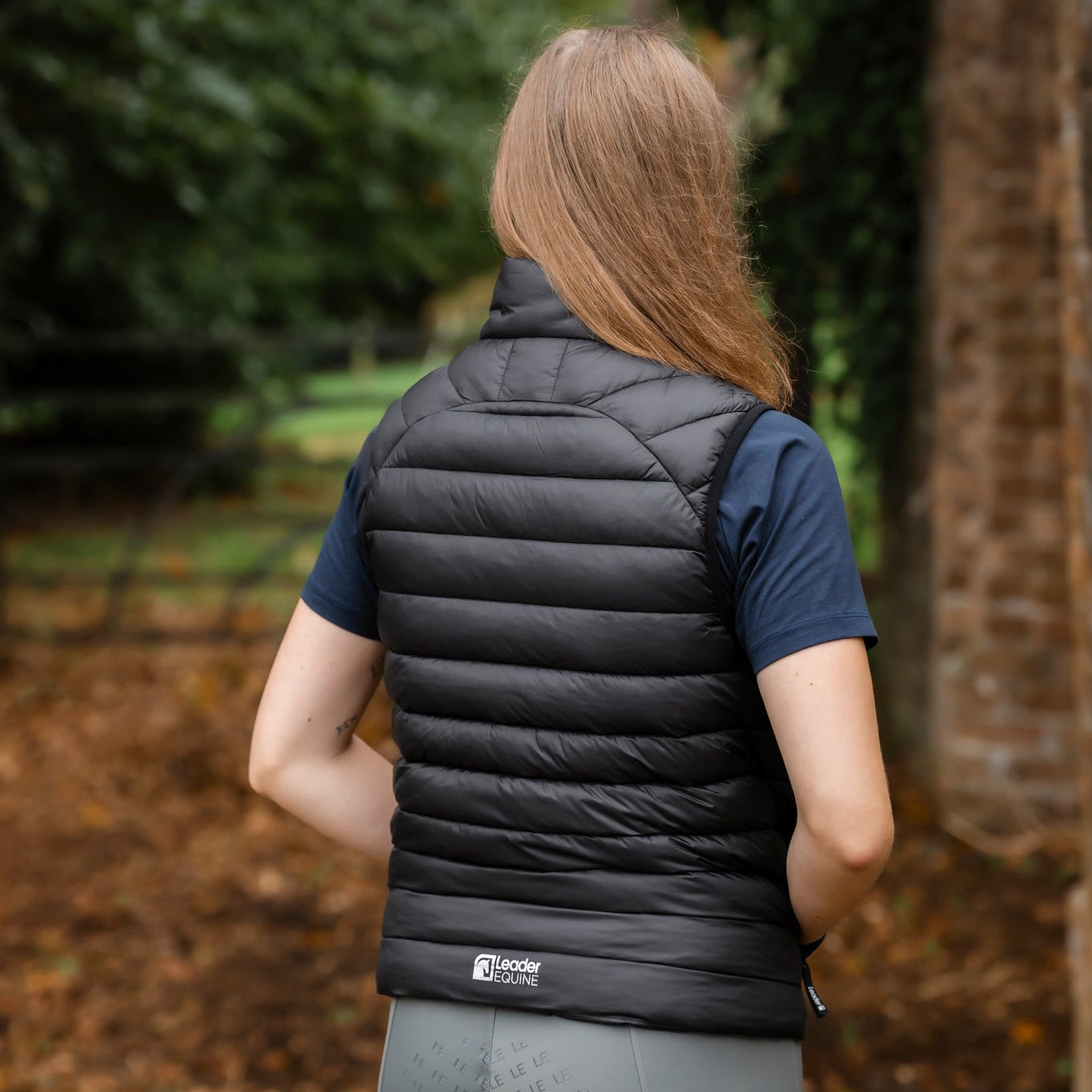 Person wearing a black puffer vest in a forest setting