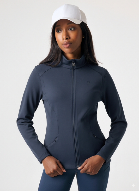 Woman wearing a dark blue athletic jacket and pants with a white cap on a light gray background