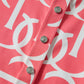 Close-up of a pink shirt with white geometric pattern and buttons.