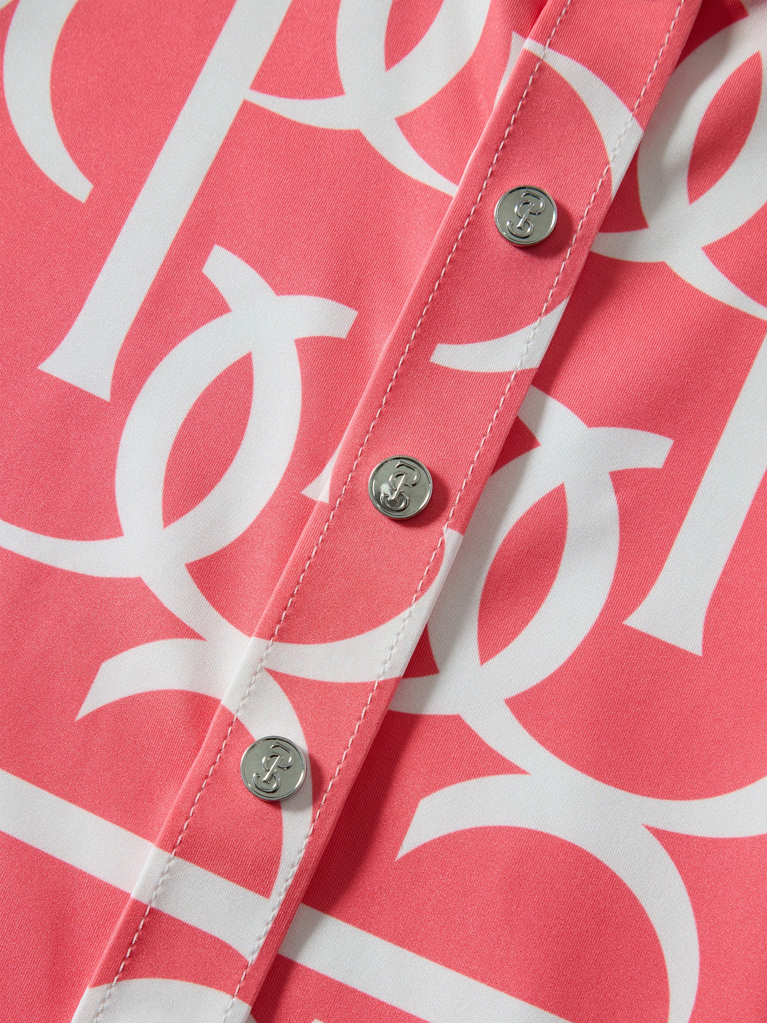 Close-up of a pink shirt with white geometric pattern and buttons.