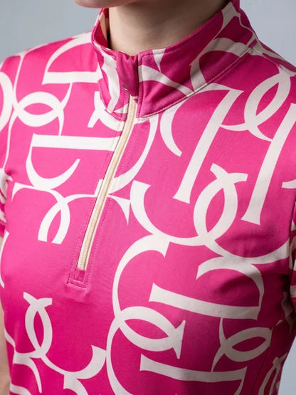 Close-up of a person wearing a bright pink short-sleeve top with a white abstract interlocking pattern and a light beige zipper at the mock neck.